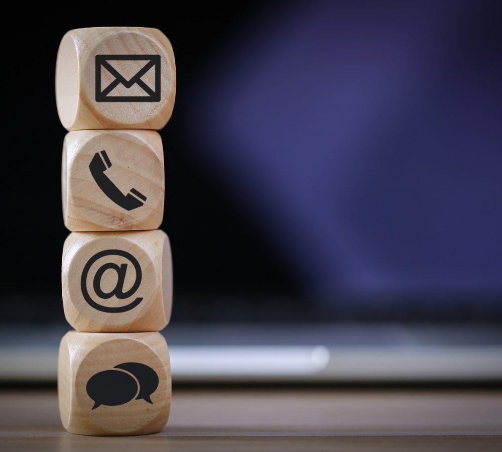 Contact Methods. Close-up of a phone, email, chat and post icons wooden block.
